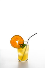 glass with ice and lemonade, a piece of orange and mint leaves with a metal reusable tube
