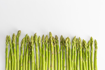 fresh asparagus is spread out at the bottom of the frame on a white background