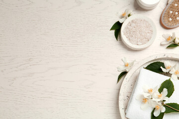 Fototapeta na wymiar Flat lay composition with sea salt and beautiful jasmine flowers on white wooden table, space for text