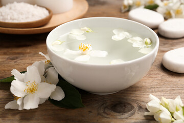 Fototapeta na wymiar Bowl with water and beautiful jasmine flowers on wooden table