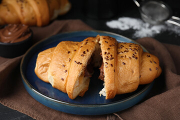 Tasty croissant with chocolate and sesame seeds on table