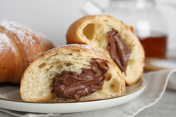 Tasty croissants with chocolate and sugar powder on plate, closeup