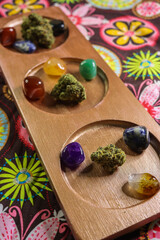 Close up of healing crystals and cannabis buds on a wooden tray.