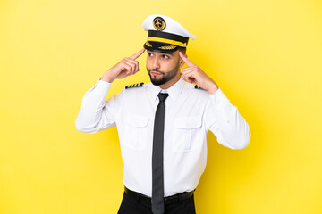 Airplane arab pilot man isolated on yellow background having doubts and thinking