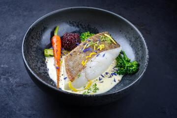 Modern style traditional fried skrei cod fish filet with baby broccoli, black red rice in lemon...