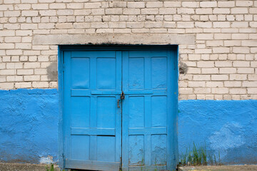Blue wooden door in a white brick  house, closed  blue wooden door