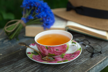 Summer still life with a cup of tea, a book and a bouquet of cornflowers.