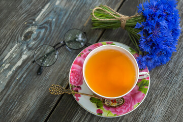 Summer still life with a cup of tea, a book and a bouquet of cornflowers.