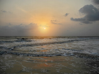 Sunset on the background of the dark gray foaming waves of the Arabian Sea. India, Kerala, Cochin
