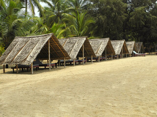 Fototapeta premium Thatched bungalows with sun loungers on the beach