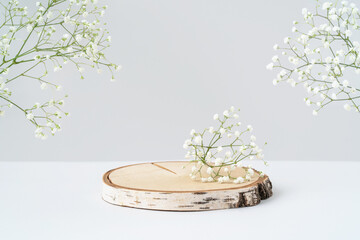 Wooden tray and flowers on grey background. Round birch saw cut for eco cosmetic product...