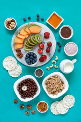 Healthy breakfast Charcuterie Boards - granola, yogurt, fruits and berries variety, nuts and flakes on the bright summer background