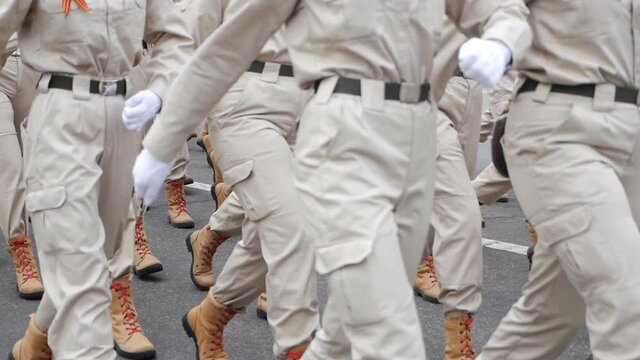 Close-up of legs and feet of military men marching down the street during the daytime parade in honor of veterans and military service. slow motion