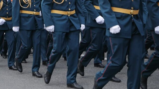 Close-up of legs and feet of military men marching down the street during the daytime parade in honor of veterans and military service. slow motion