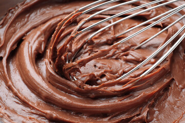 Whipping chocolate cream with balloon whisk, closeup view