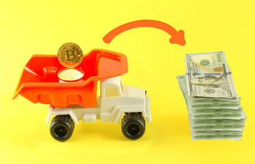 A toy car on a yellow background with bitcoin and a stack of dollars next to it. Concept to convert bitcoin to dollars