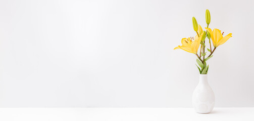 Home interior with decor elements. Yellow lilies in a vase on a light background