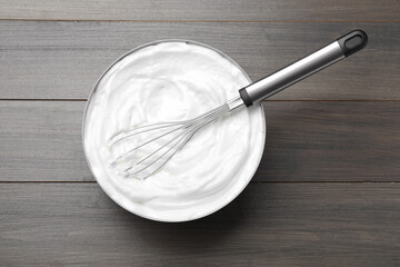 Fototapeta na wymiar White cream with balloon whisk on grey wooden table, top view