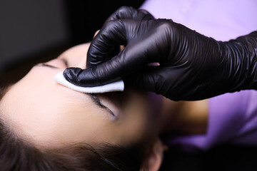 the tattoo artist prepares the client's eyebrows for the procedure of permanent makeup wipe with a cotton sponge