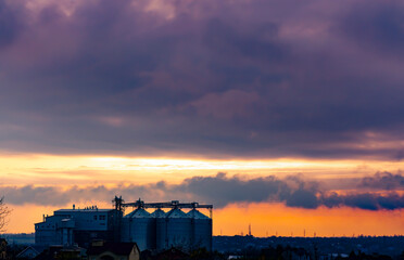 View of the modern outdoor grain storage silos at sunset and big cloudy sky. Granary elevator © MTX