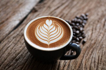 Close up hot coffee cup topping by leave latte art shape serve on wooden table