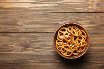 Pretzels in ceramic bowl on wooden background with empty space for text. Pretzels flat lay, top view, copy space