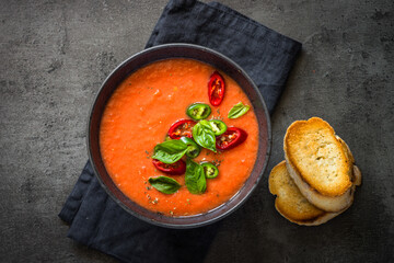Tomato soup or gazpacho soup at black table. Vegan dish. Top view with copy space.