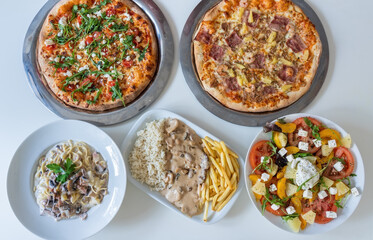 Variety of different cultural dishes in table of Indian food plates Pizza,salad, rice, meat, vegetables. Food panorama. Top view