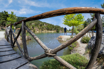 Fototapeta na wymiar Beletsi Lake in Athens - Greece. Panoramic view to Beletsi Lake while standing on the wooden bridge of the lake and looking through the wooden railings. Man is standing under a tree admiring the view