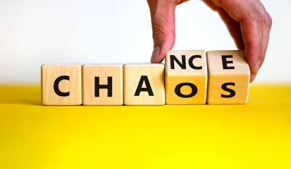 Chance or chaos symbol. Businessman turns wooden cubes and changes the word 'chaos' to 'chance'....