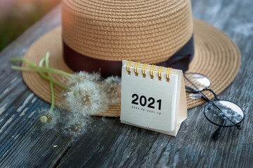 Summer 2021 calendar, summer straw hat and fluffy dandelions.
