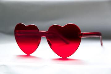 Red heart shaped sunglasses on light background, closeup