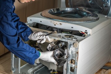 Mechanic or technician is repairing old washing machine.