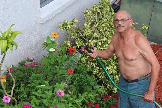 Senior Citizen Watering Flowers with Garden Hose