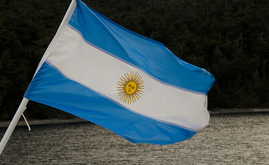 Argentine flag waving on boat, with lake and mountains in the background