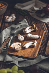 Dark photography of mushrooms, asparagus, bread, garlic and plums on a table of old wood. Vegetables recipe of for autumn or winter. Moody picture of seasonal cultivated fungus on a wooden table.