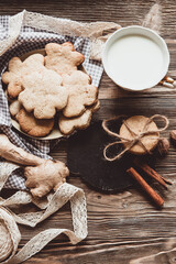 Close up of homemade ginger cookies, cinnamon, ginger with cup of milk on a towel wooden table. Copy space. Retro toned image, flat lay