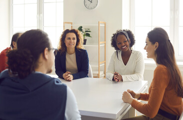 Team of mixed race people sitting around office table and discussing business projects together....