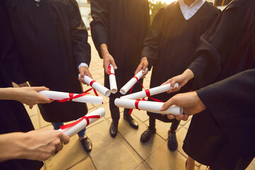 Graduate.Graduation ceremony celebration concept. Hand of college graduates gifted students holding diploma degree certificate joining together in circle. Completed study in academy or university