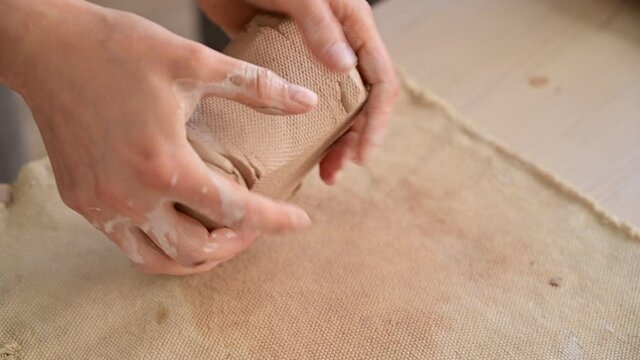Woman working with raw piece of clay during masterclass