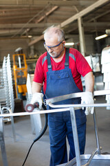 Blue collar worker polishing a piece of metal in a manufacturing facility