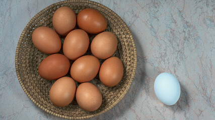 several fresh chicken eggs in a straw basket on a wooden background. Healthy eating concept.