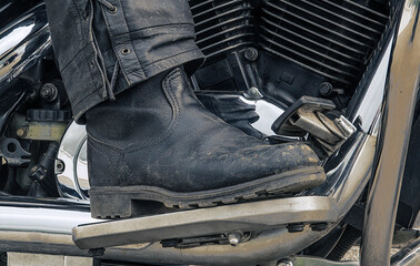 Old motorcycle boots on the side of the motorcycle.
