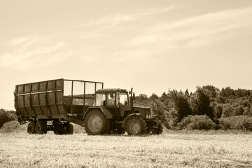 Tractor with a trailer in the field for agricultural work. 