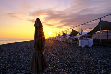 beautiful landscape. sunbeds on the beach at sunset on the shore of a colorfully orange colored...