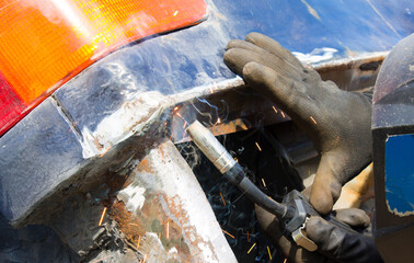 Worker in helmet repair detail in car service