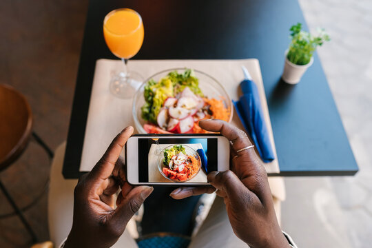 Anonymous black man's hands taking a picture of the healthy vegetable salad.