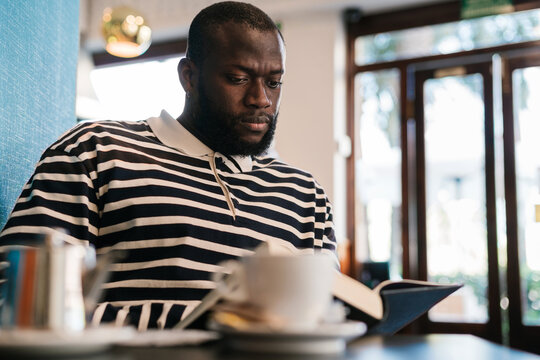 Black man reading inside a coffee shop
