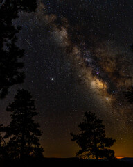 Via lactea en las montañas de Arizona abajo de las estrellas con arboles de pinos con vista de estrella fugaz y Júpiter durante atardecer
