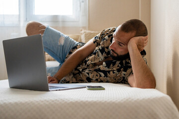 Modern man watching a film in his laptop at bedroom